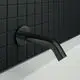 Schwarzer Wandauslauf von Ideal Standard mit runder Rosette. An der Wand montiert, bildet er einen fließenden Übergang zu einer weißen Badewanne.